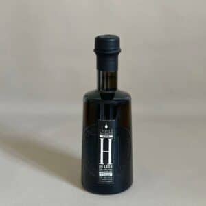 Bouteille en verre de 25 cl d'huile d'olive vierge extra "L'Huile Originelle H" du Domaine de Leos, montrant l'étiquette avant avec le logo et la description du produit. Produit artisanal français, fruité et aromatique